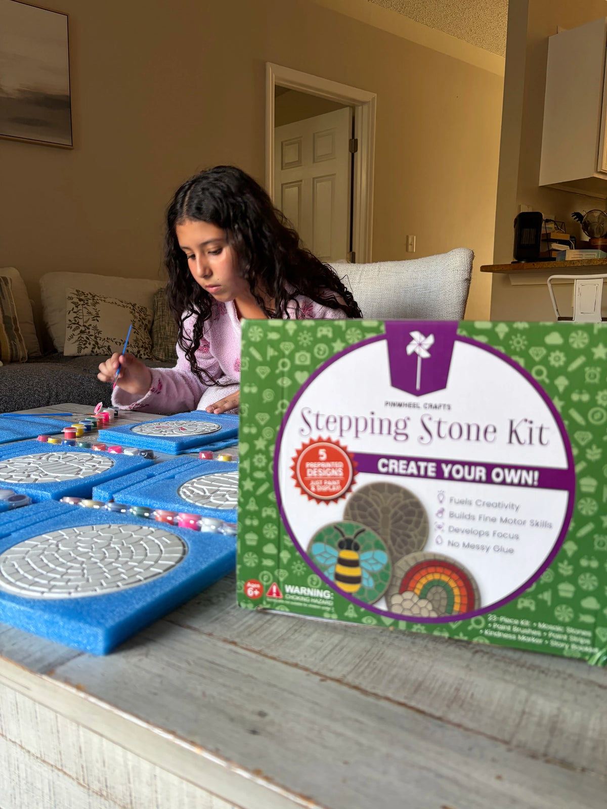 Child working on a make your own stepping stone kit craft project in a home setting.