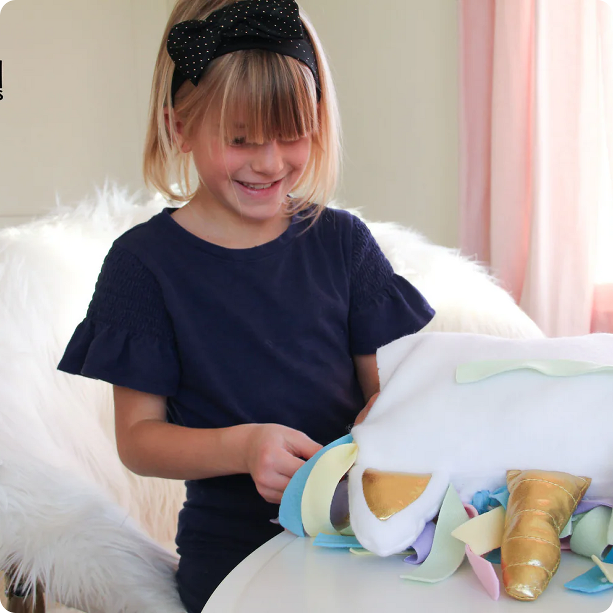 Young girl playing with a colorful unicorn plush kit on a white couch