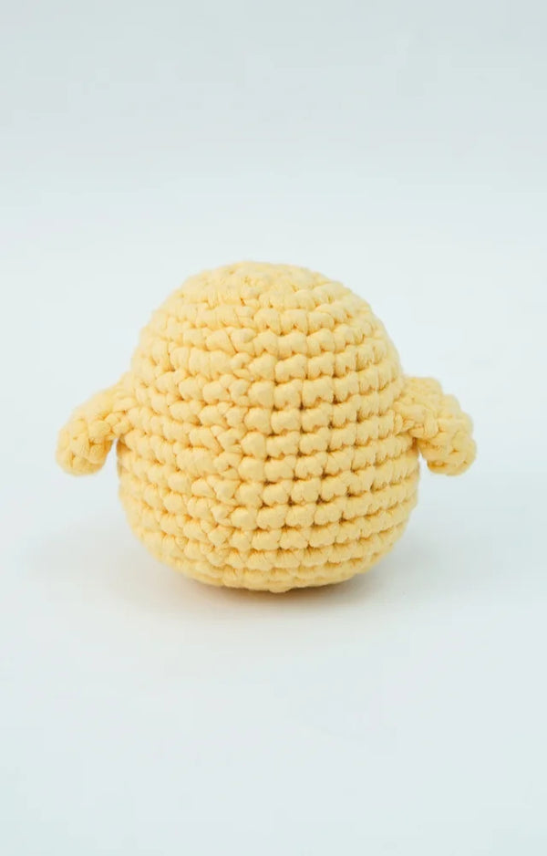 The crocheted yellow chick seen from behind, showing its round body and both small wings