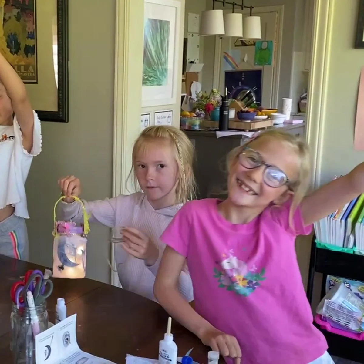 Two smiling girls beside a glowing fairy jar they decorated together at a fairy craft party
