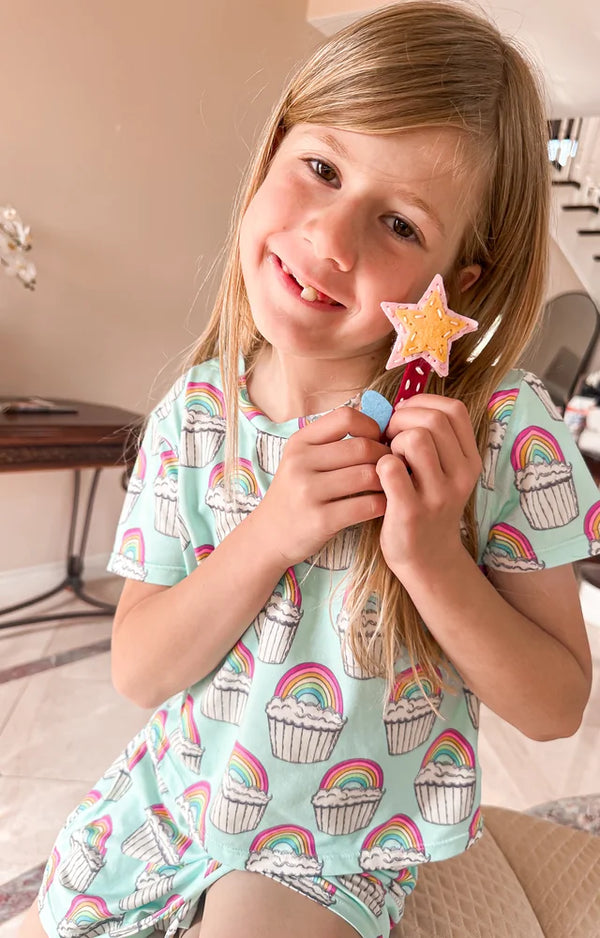 Girl in rainbow pajamas holding up the felt star wand she sewed