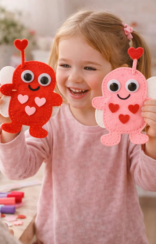 Girl laughing as she holds up two finished felt love bugs, one red and one pink