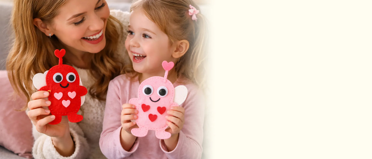 Mother and daughter laughing together, each holding a felt love bug from the kit