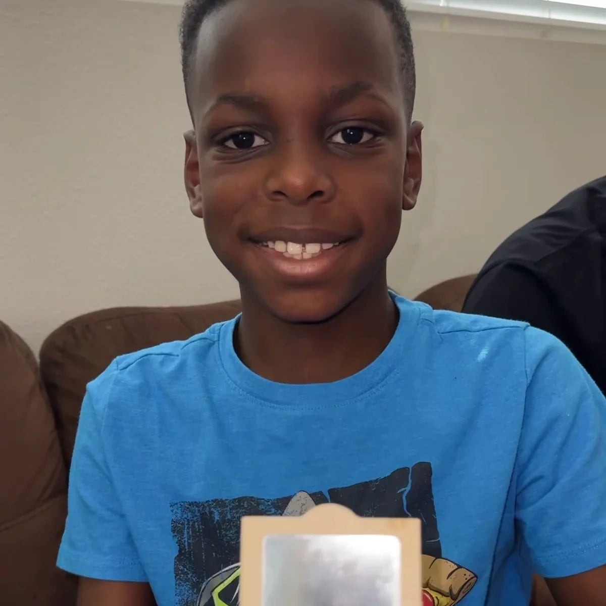 Smiling boy in a blue T-shirt holding his finished wooden music box with the mirror lid open