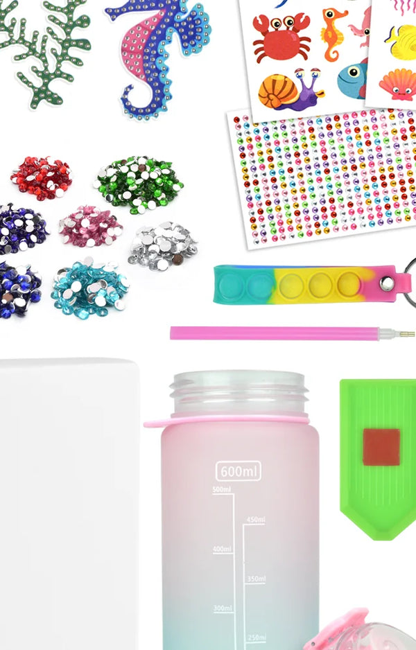 Sea creature stickers, gem piles, the strap, gem pen and tray beside the plain pink bottle