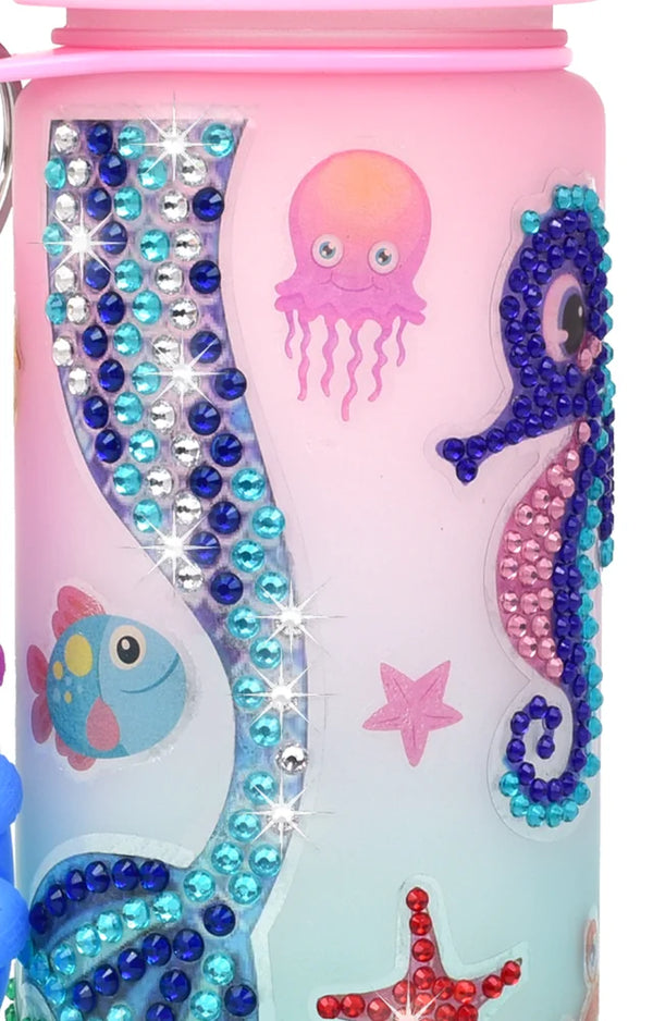 Close-up of a gem mermaid tail, seahorse, jellyfish and fish stickers on a pink bottle