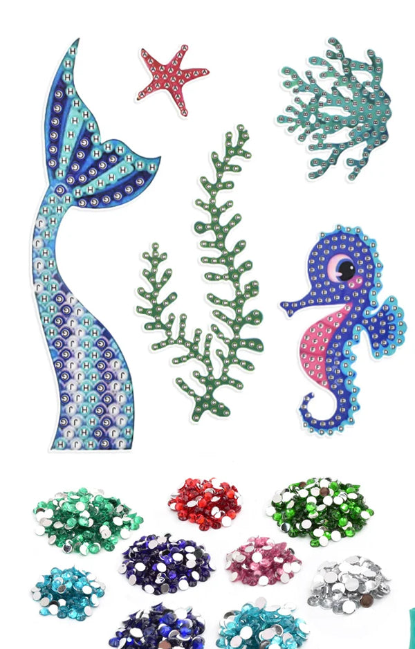 Mermaid tail, starfish, coral, seaweed and seahorse stickers above piles of colored gems