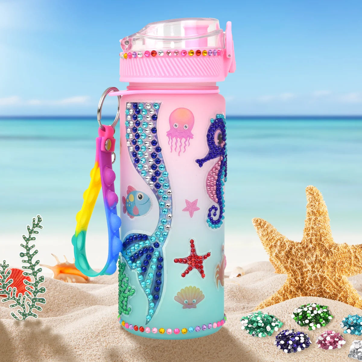 Finished mermaid water bottle with a bubble-pop strap standing on the sand by the sea
