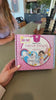 A girl reads the instructions, stitches a felt unicorn, and smiles with it finished