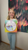 A girl shows the kit, ties the fleece strips, stuffs the pillow and hugs her finished unicorn