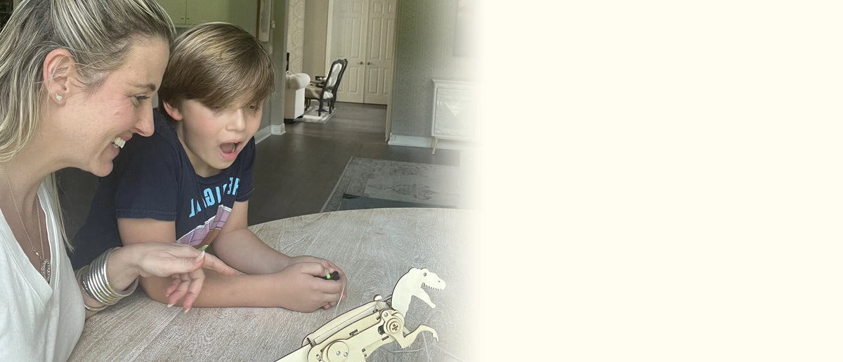 Mom laughing as her son presses the controller button and their wooden T-rex starts to move