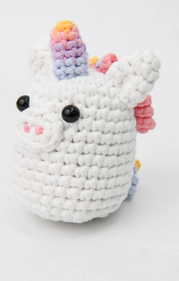 Three-quarter view of the crocheted rainbow unicorn showing its rainbow horn and curly mane