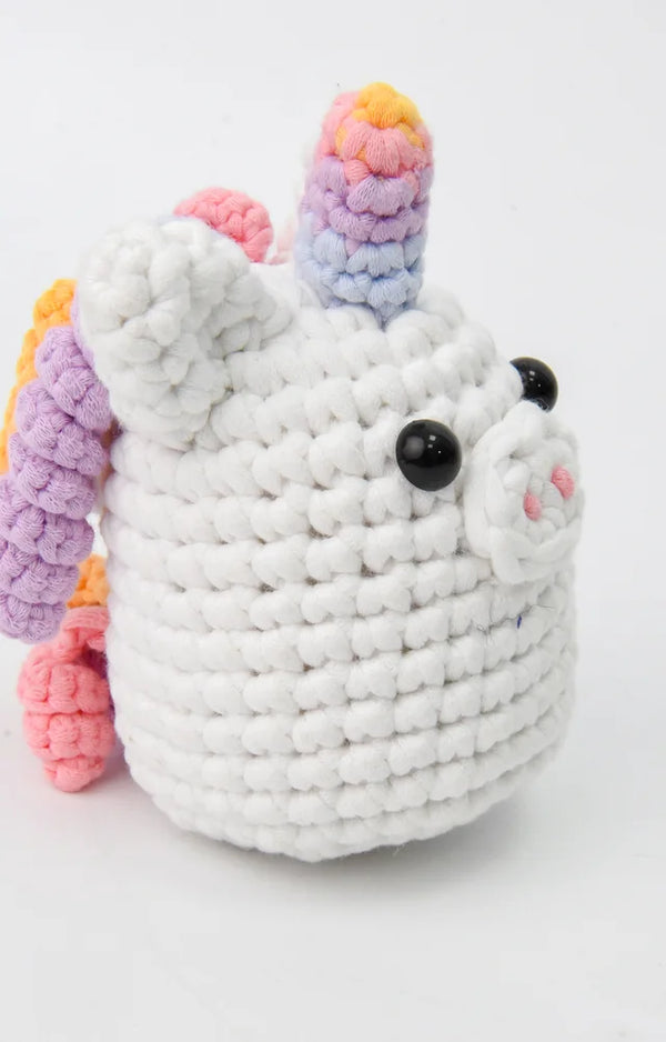 Side view of the crocheted rainbow unicorn with its curly rainbow mane and rainbow tail