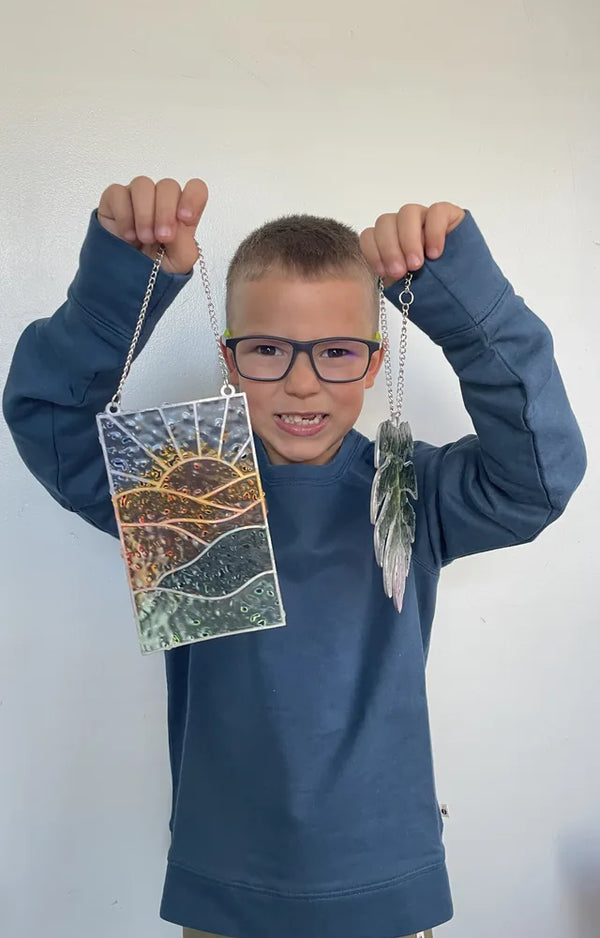 Boy holding up both finished stained glass suncatchers