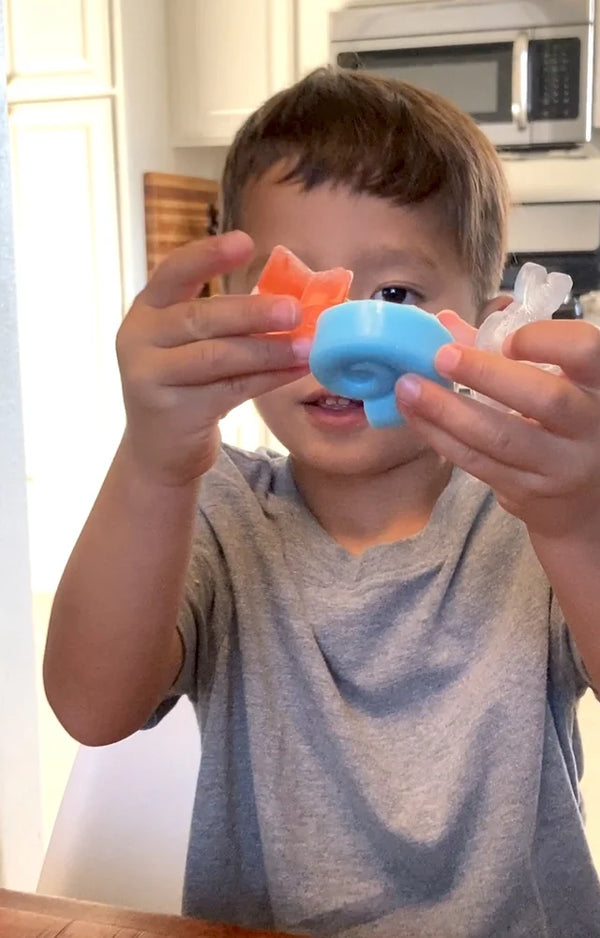 Boy holding three colorful sea life soaps up toward the camera