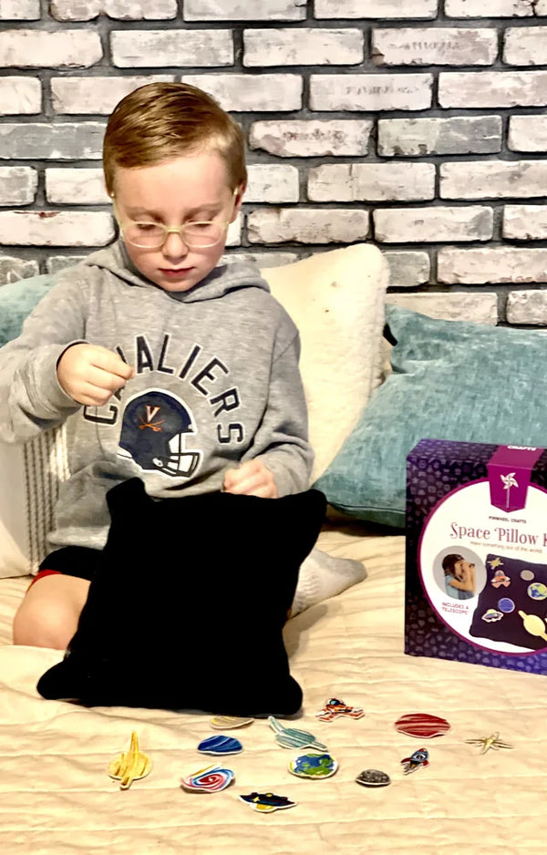 A boy on the bed with the space pillowcase, its patches laid out and the kit box beside him