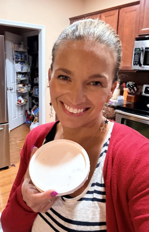 Smiling woman in her kitchen holding up the finished white terrazzo trinket dish she made