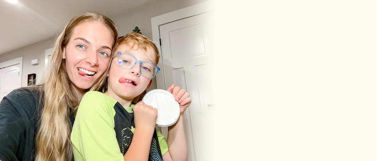 Mom and her son pulling silly faces as the boy holds up the terrazzo trinket dish they made together