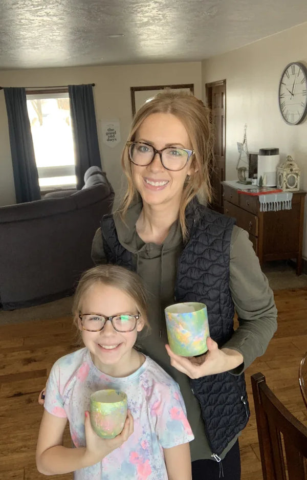 Mother and daughter standing in their living room, each holding a finished marbled pot